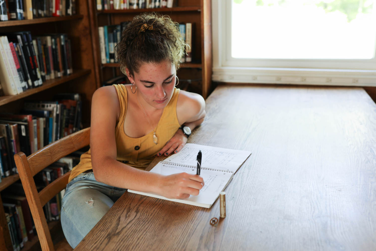Girl in yellow shirt writing in a notebook